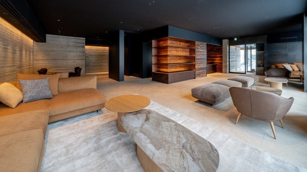 Cedars Hotel lounge with velvet sofas, sculptural stone and wood coffee tables, and a backlit timber feature wall dividing the space